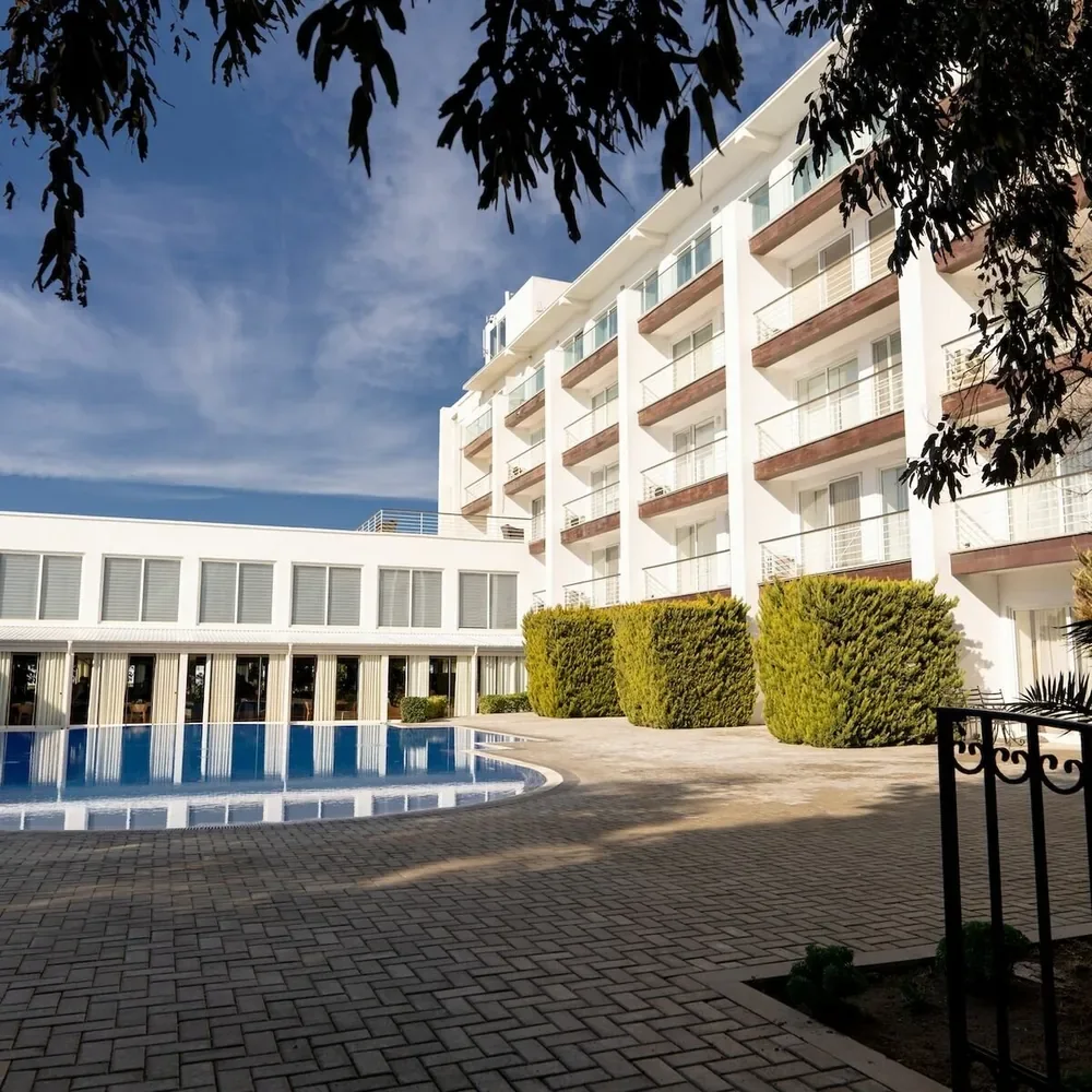 Белый корпус Sea Breeze Hotel и бассейн во дворе — ориентир рядом с точкой